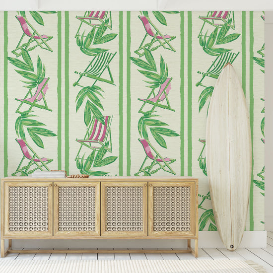 vertical linear grasscloth wallpaper print with a beachy design of green leaves and stripes paired with green and pink beach chairs arranged in a vertical oversized stripe Grasscloth Natural Textured Eco-Friendly Non-toxic High-quality  Sustainable practices Sustainability Interior Design Wall covering bold Seaside Coastal Seashore Waterfront Vacation home styling Retreat Relaxed beach vibes Beach cottage Shoreline Oceanfront Nautical