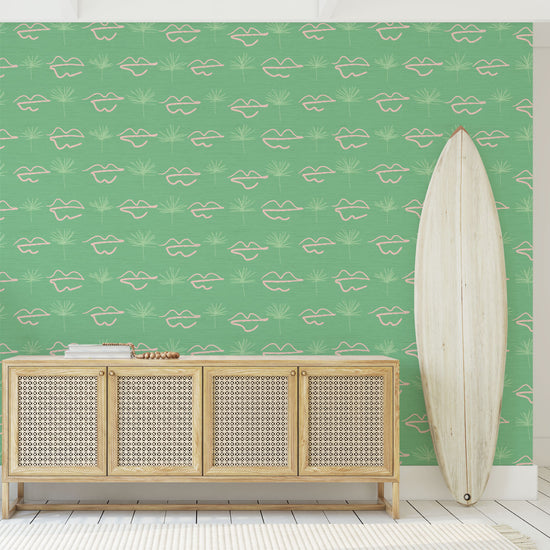 bright green based printed grasscloth wallpaper with hand drawn pink lips arranged opposite sketched tonal green palm tree arranged in a gridlike pattern.