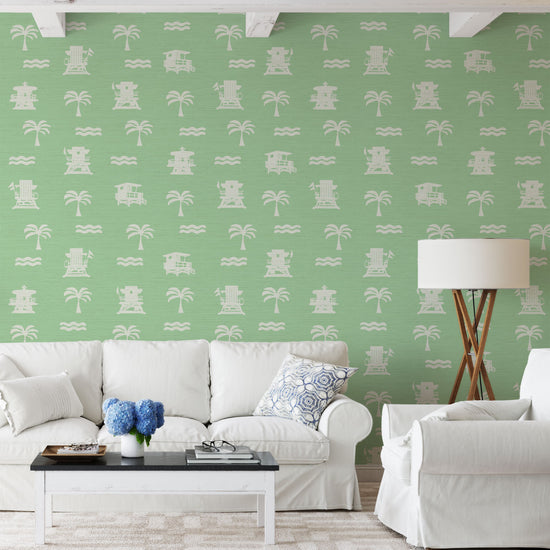 living room light green (mint) base grasscloth wallpaper with white print of lifeguard stands, waves and palm trees in a mini icon print