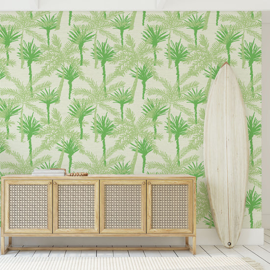 grasscloth printed wallpaper with a cream base color with tonal linear and overlapping palm trees in a variety of shades of green ranging from light, medium to dark seafoam green.