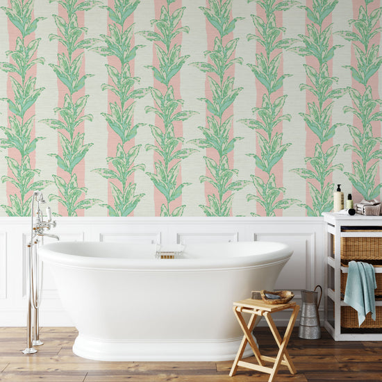 printed grasscloth with light pink and white vertical cabana stripes overlayed with light green and aqua shades of palm leaves also arranged in a vertical stripe cascading down the paper.