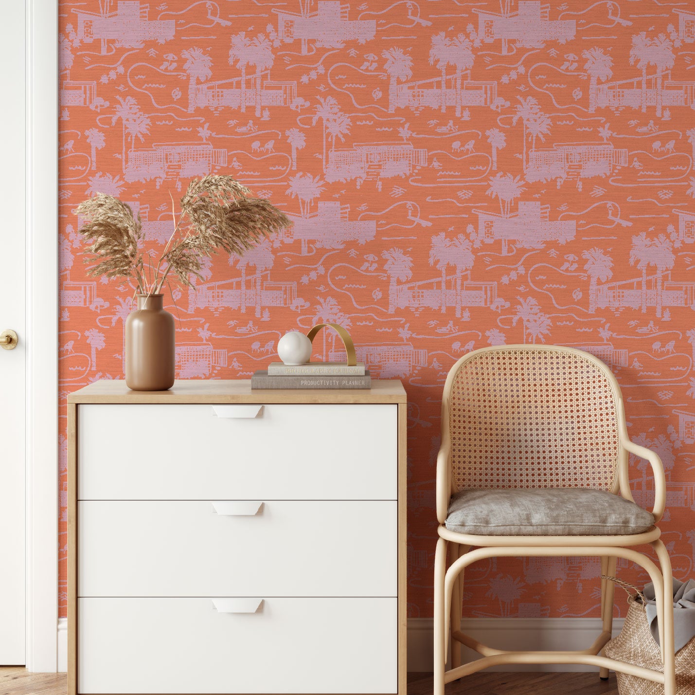 dresser and chair in front of grasscloth toile printed wallpaper with mid century modern houses inspired by palm springs featuring swimming pools, palm trees and secret suntanning ladies in this hand drawn one color printed design with coral base and light pink print