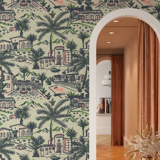 Retail store fitting room with grasscloth wallpaper in modern toile print with Spanish style architecture houses, palm trees, pools, 1980s vintage cars mountains in the background. The print is a light green base with dark green, bright neon green and splashes of neon coral print